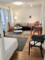Moderni olohuone, jossa on sohva, kaksi nojatuolia, pieni pöytä ja lamppu.