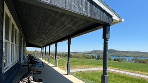 Une véranda couverte offrant une vue sur un lac et des collines.