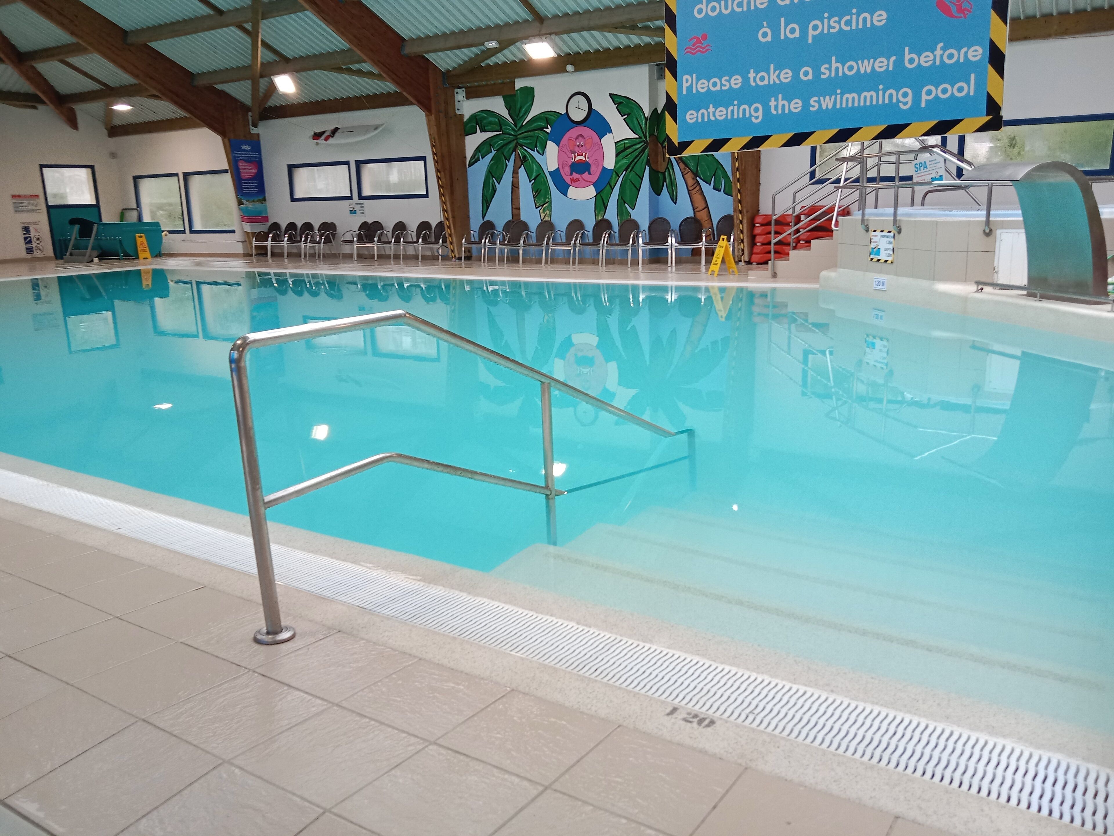 Une piscine intérieure avec un panneau indiquant qu’il faut prendre une douche avant d’y entrer.