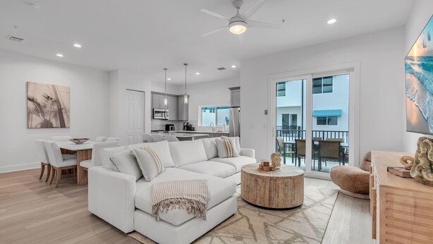 A modern living room with a white sofa, a round coffee table, and a dining area. - Azul Townhomes A3 and A4 - Sunrise/sunset (Madeira Beach)