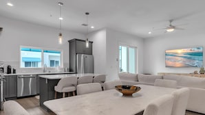 A modern kitchen with a central island, grey cabinetry, and stainless steel appliances. - Azul Townhomes A3 and A4 - Sunrise/sunset (Madeira Beach)