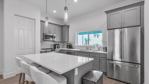 A modern kitchen with a central island, stainless steel appliances, and a view of the outside. - Azul Townhomes A3 and A4 - Sunrise/sunset (Madeira Beach)