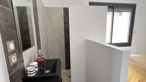 Een moderne badkamer met een zwart wastafelmeubel, een spiegel en een raam.