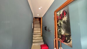 Un pasillo con una escalera, un banco rojo y un cuadro en la pared.