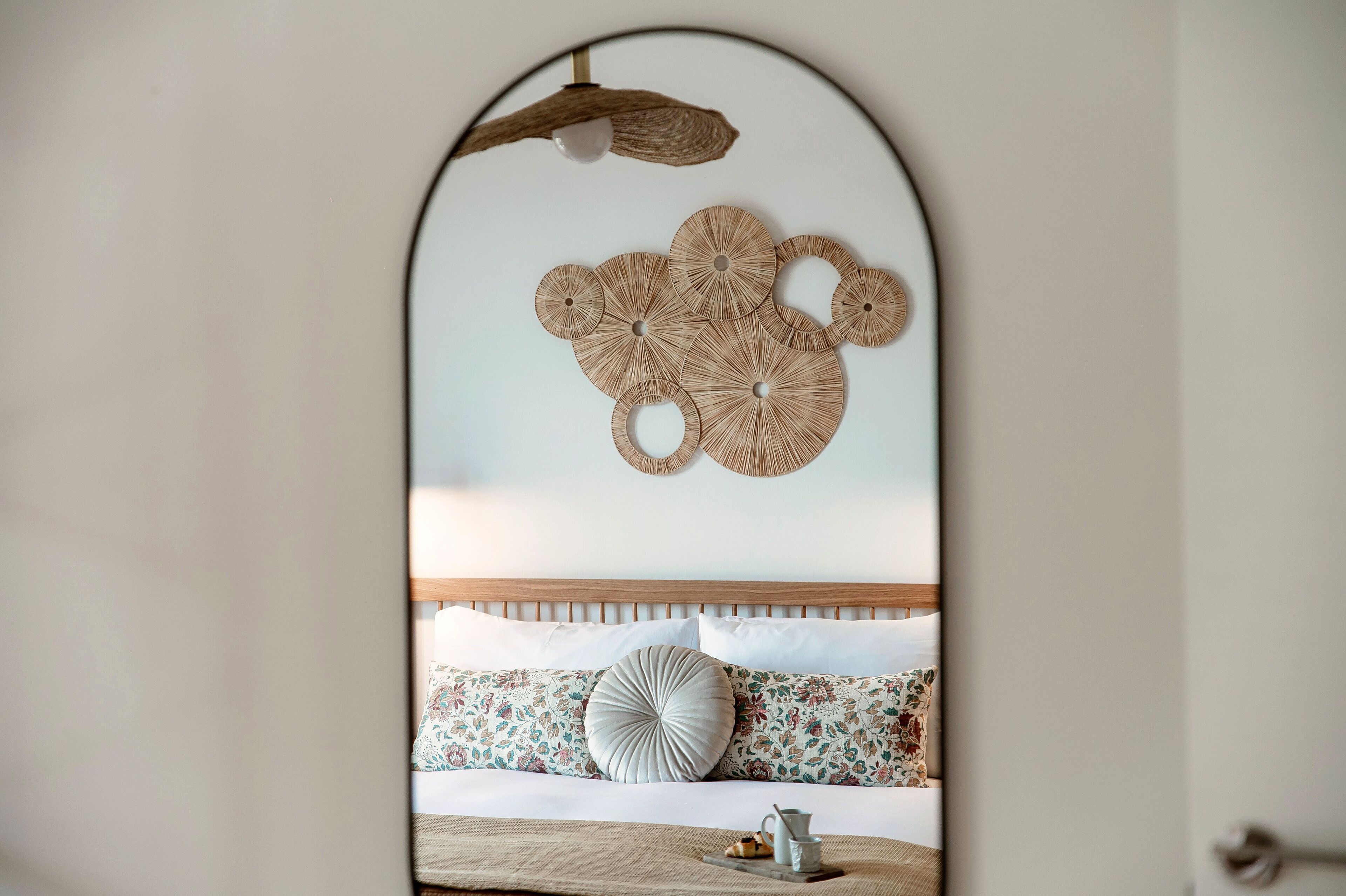 Ein Schlafzimmer mit einem Holz-Kopfteil, gemusterten Kissen und einer Wanddekoration.