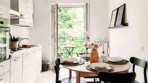A modern kitchen with white cabinets, a dining table set for two with plates, glasses, and a candle. - Moonlight (San Fermo della Battaglia)