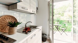 A modern kitchen with white cabinets, a stainless steel sink, and a view of a balcony with outdoor furniture. - Moonlight (San Fermo della Battaglia)