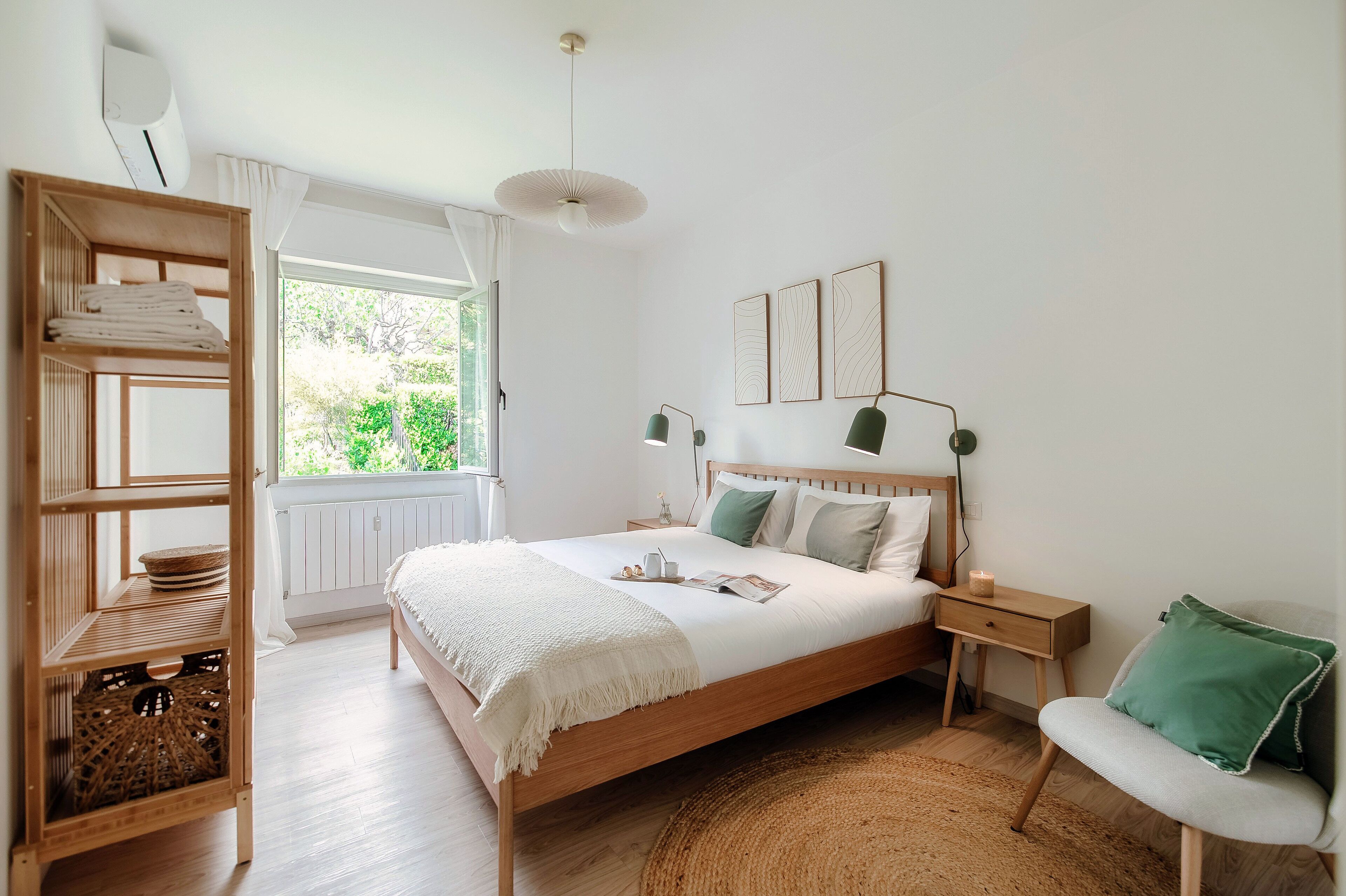 Un dormitorio con una cama de madera, mesitas de noche, un tapete tejido y vistas a zonas verdes.