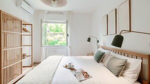 A neatly arranged bedroom with a bed, bedside table, lamp, and a window with curtains. - Moonlight (San Fermo della Battaglia)
