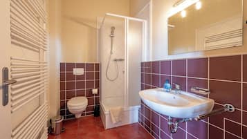 A bathroom with a white toilet, a shower, and a sink with a mirror above it.
