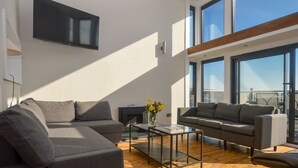 A modern living room with a sectional sofa, a glass coffee table, and a fireplace. - Cliff Top - Bubbling Springs - spectacular sea views. Sleeps 4 guests (Wemyss Bay)