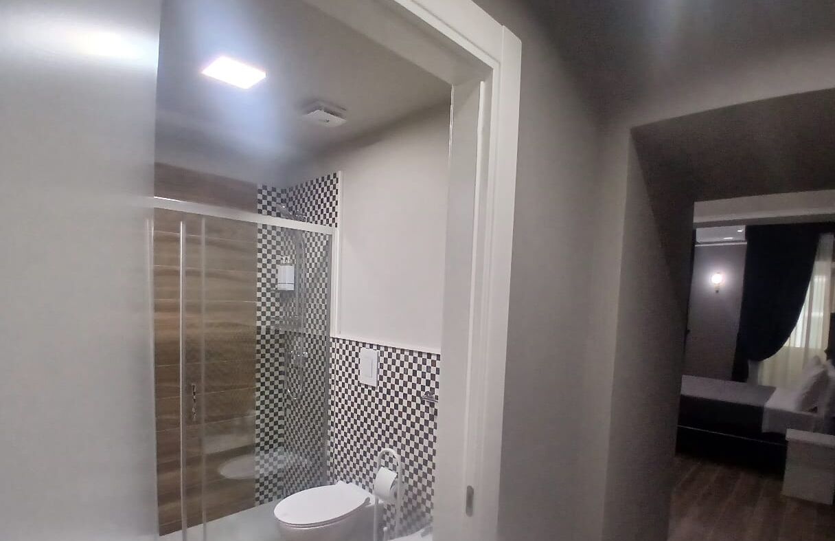 Un baño moderno con cabina de ducha de vidrio, inodoro y tocador con espejo.