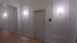 A hallway with three doors, each with a light fixture above. The walls are plain, and the floor is wooden. - Dimora Neapolis (Naples)