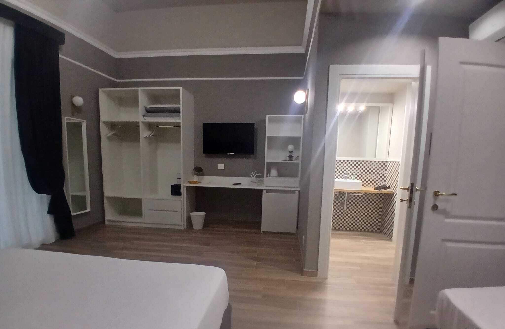 A hotel room with a bed, a desk, a TV, and a kitchenette.