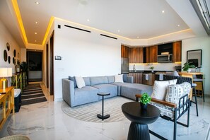A modern living room with a grey sectional sofa, a round black coffee table, and a patterned armchair.