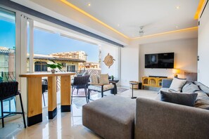 A modern living room with a sofa, a dining table, and a TV.