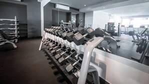 A gym with rows of dumbbells, exercise machines, and a large mirror. - Rooftop Pool + Gym | Romantic Zone Gem (Puerto Vallarta)