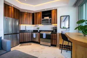 A modern kitchen with wood cabinets, stainless steel appliances, and a marble floor. - Rooftop Pool + Gym | Romantic Zone Gem (Puerto Vallarta)