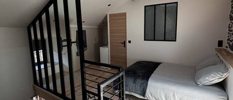 Ein Schlafzimmer im Loft-Stil mit Dachfenster, einer Holztreppe und einem Bett mit Kissen.