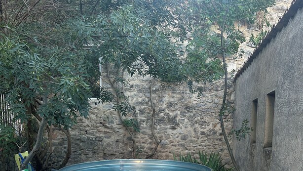 Un espace patio comprenant un jacuzzi, deux chaises longues à rayures et un mur en pierre.