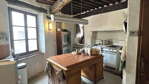 Une cuisine rustique avec des poutres apparentes, un îlot central et une cuisinière.