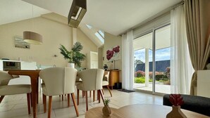 Un salon moderne comprenant un coin repas, une cuisine et une grande porte-fenêtre coulissante donnant sur un balcon.