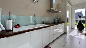 Une cuisine moderne dotée d’un grand îlot central, de meubles blancs et d’une fenêtre laissant entrer la lumière naturelle.