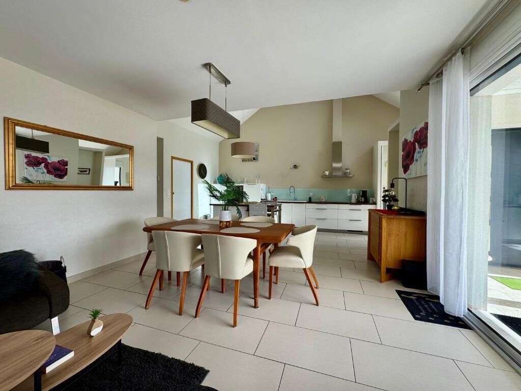 A modern living room with a dining area, kitchen, and large sliding glass doors to a balcony.