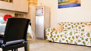 A kitchen with a stone ceiling, a dining area with a black chair, a refrigerator, and a sofa with a floral pattern. - Once upon a time. Apartment with typical star vault and barrel vault. (Nardò)