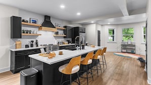 A modern kitchen with a central island, black cabinetry, and wooden bar stools.