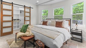 A bedroom with a large bed, a bench, a nightstand, and a sliding closet.
