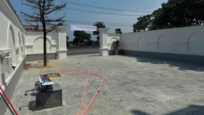 Un patio con suelo de baldosas, una manguera roja y un árbol.