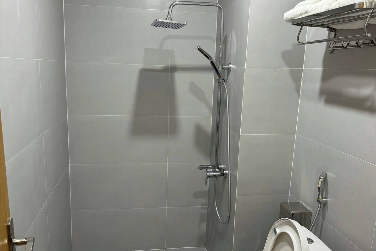 Casa de banho moderna com chuveiro, sanita e lavatório.