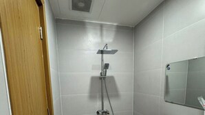 Un baño con ducha, lavamanos y espejo.
