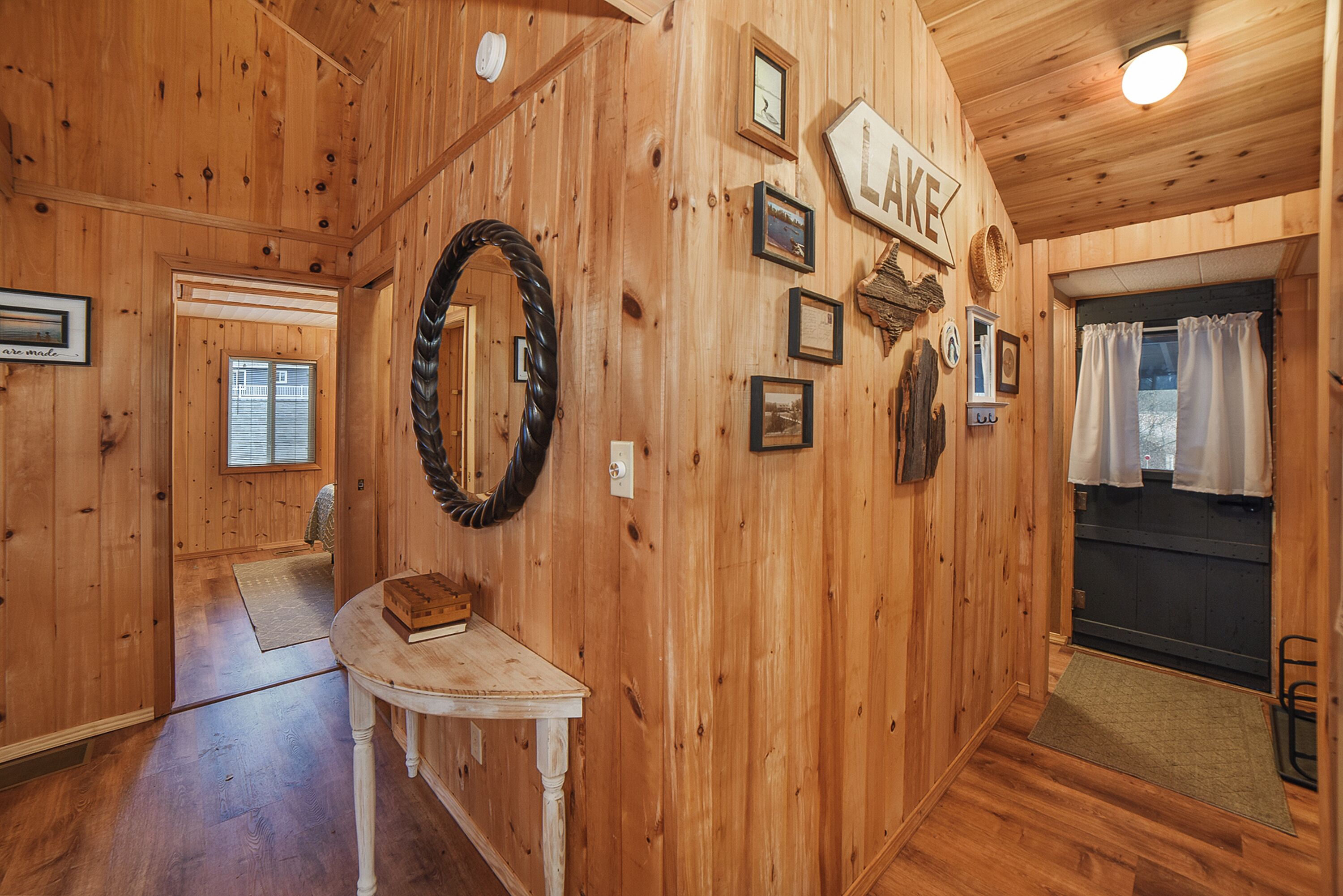 Un intérieur en bois avec une cheminée, un miroir, des tableaux encadrés et une enseigne sur laquelle on peut lire « LAKE ».