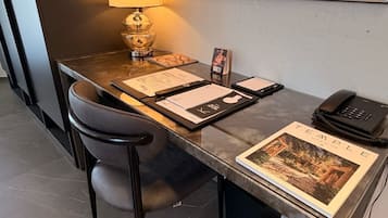Escritorio de hotel con una lámpara, un teléfono, un cuadro enmarcado y un libro titulado 'TEMPLE'.
