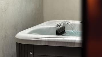 A modern bathroom with a freestanding bathtub, a towel on a pedestal, and a textured wall.