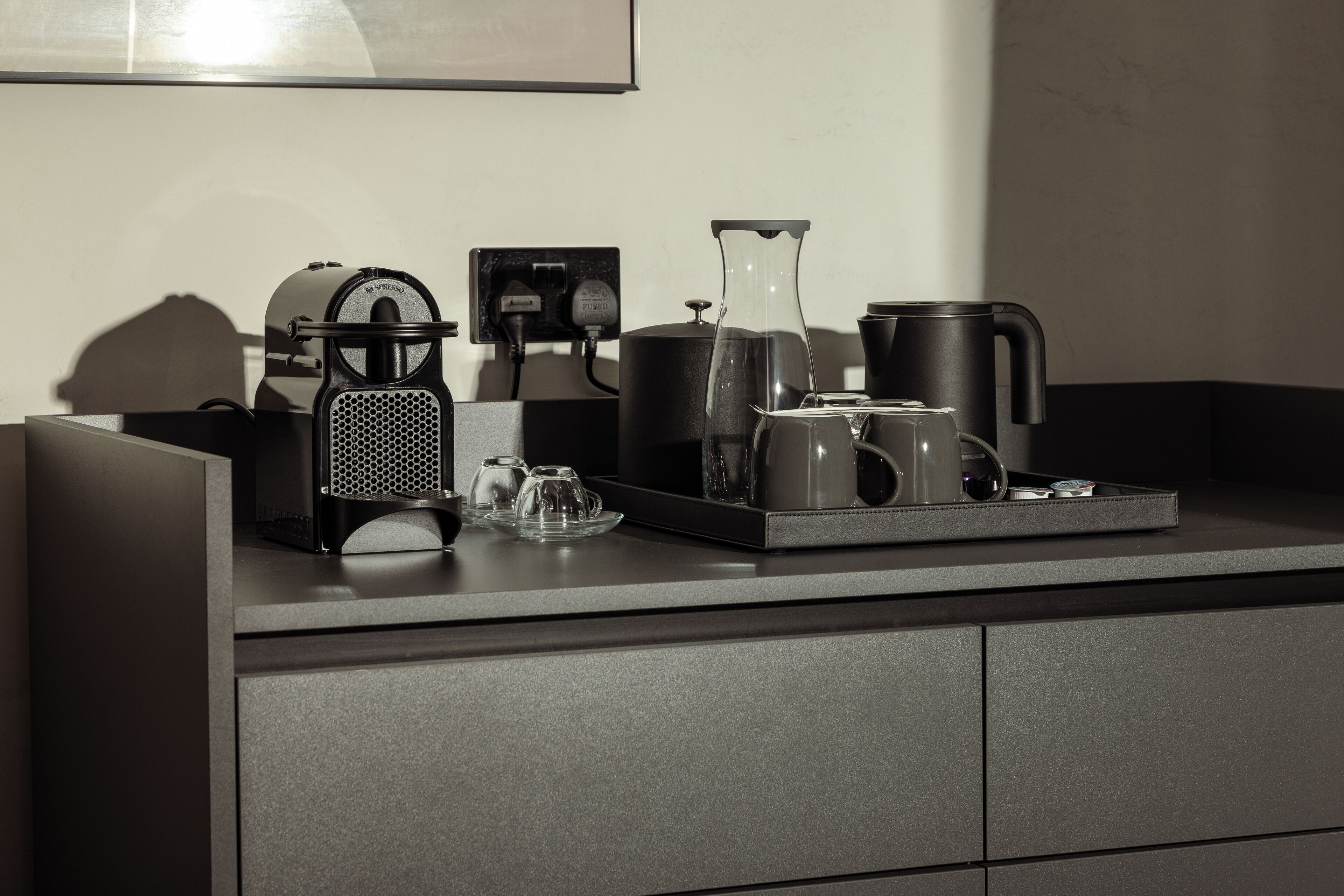 Een moderne keuken met een koffiezetapparaat, waterkoker en theepot op het aanrecht.