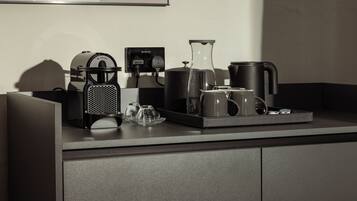 Een moderne keuken met een koffiezetapparaat, waterkoker en theepot op het aanrecht.