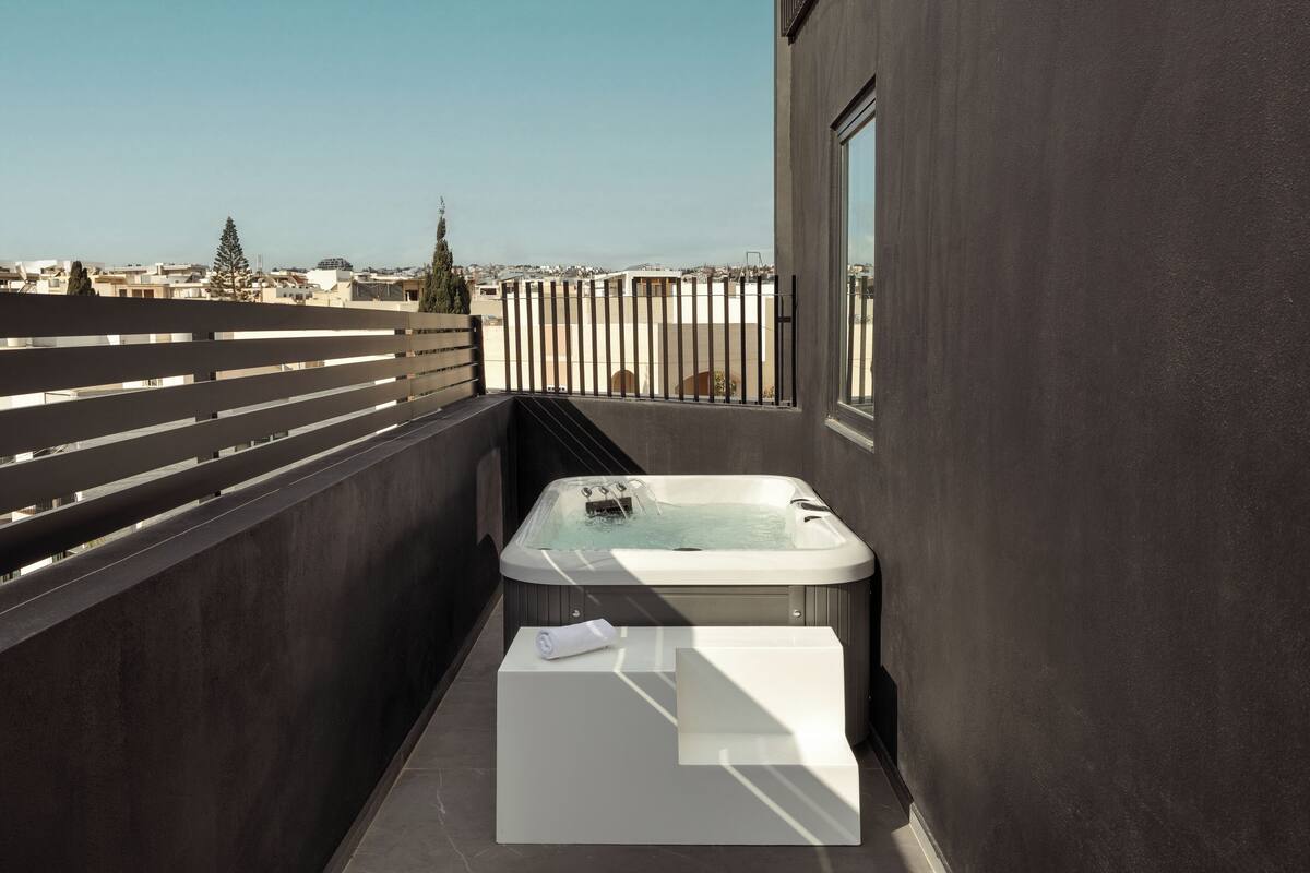 Un balcón con un jacuzzi, una toalla blanca y vistas a la ciudad.