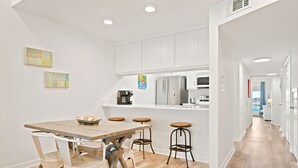 A modern kitchen with white cabinets, a wooden dining table, and bar stools. - NEW LISTING!!! Gulfside Villa 2B-  AMAZING beachfront view  NO HASSLE CHECK OUT (Perdido Key)