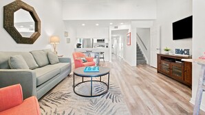 A spacious living area with a sofa, armchair, coffee table, and a decorative mirror. A ceiling fan and recessed lighting are visible. - NEW LISTING!!! Gulfside Villa 2B-  AMAZING beachfront view  NO HASSLE CHECK OUT (Perdido Key)