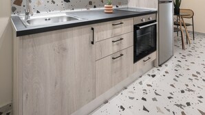 A modern kitchen with a granite backsplash, stainless steel sink, and built-in oven. - Phedra Studios Nilie Hospitality MGMT (Thessaloniki)