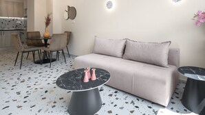 A modern living room with a beige sofa, two black marble tables, and a potted plant with pink flowers. - Phedra Studios Nilie Hospitality MGMT (Thessaloniki)