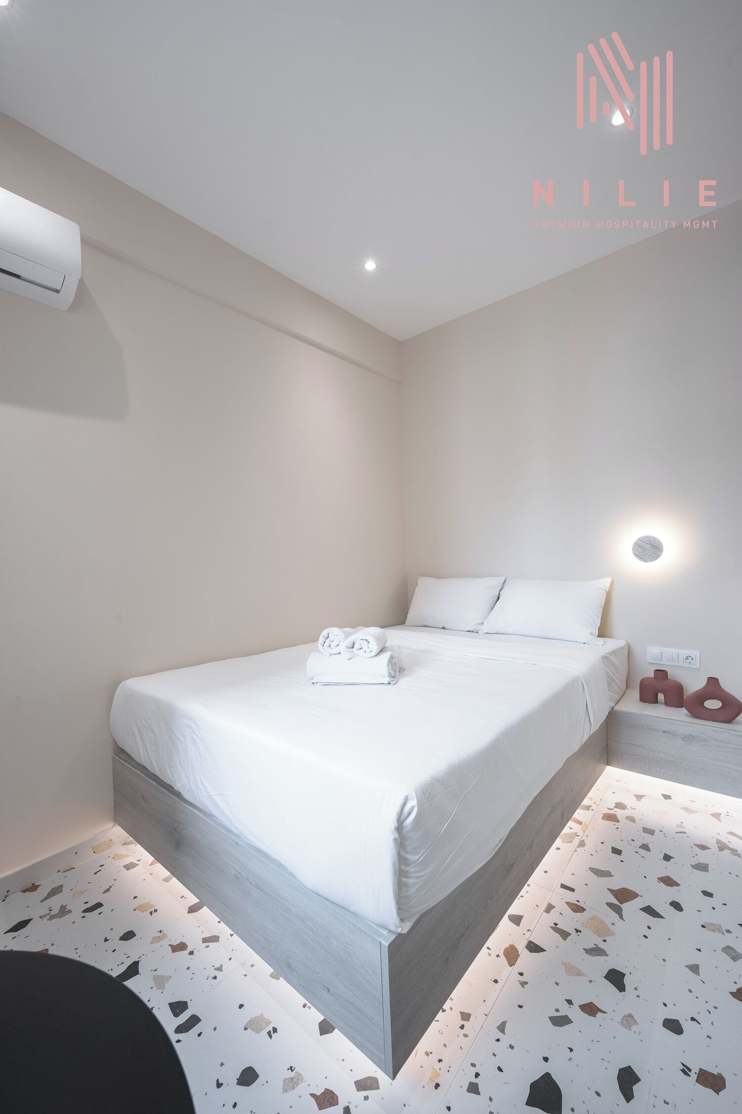 Ein modernes Hotelzimmer mit einem großen Bett, einem Nachttisch und einer Wand-Klimaanlage.