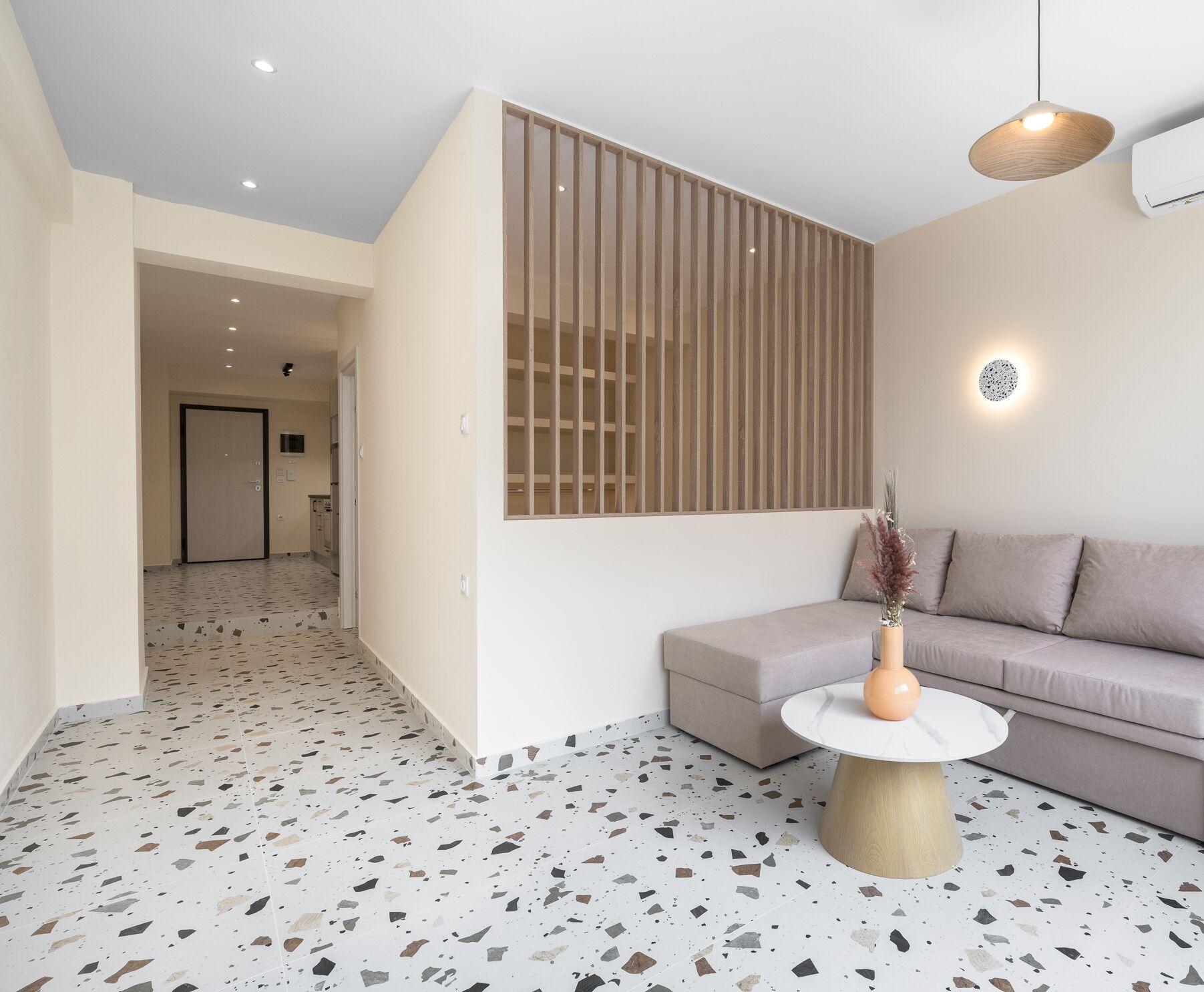 Een moderne woonkamer met een bank, een rond bijzettafeltje en een decoratieve vaas.