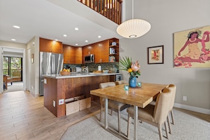 Una cocina moderna con armarios de madera, electrodomésticos de acero inoxidable y un comedor con una mesa y sillas de madera.