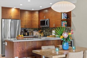 Una cucina moderna con mobili in legno, elettrodomestici in acciaio inossidabile e un'isola centrale con posti a sedere.