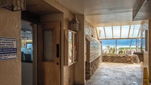 Un restaurante con vista a la playa, un letrero que indica estacionamiento reservado y un aviso de precaución sobre el piso.