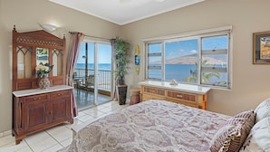 Un dormitorio con cama, cómoda y vista al océano.